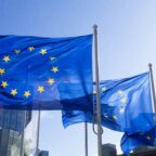 European Union flags waving on flagpoles against a blue sky