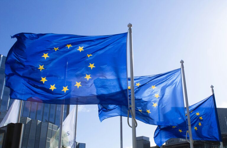 European Union flags waving on flagpoles against a blue sky