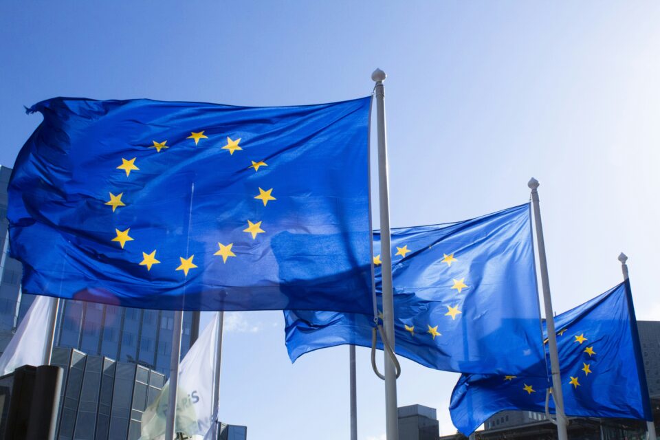 European Union flags waving on flagpoles against a blue sky